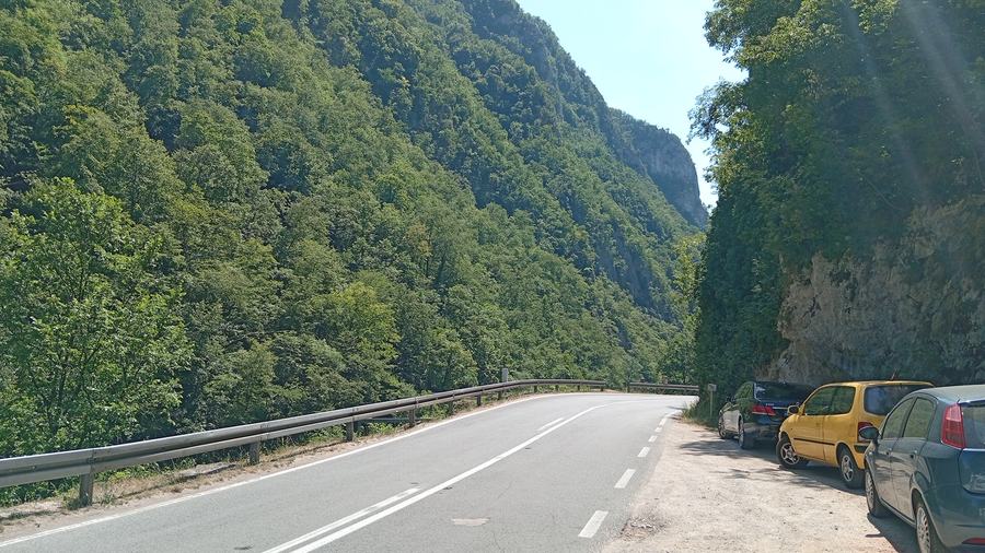 Road through the Vrbas canyon with cars parked at a river access point