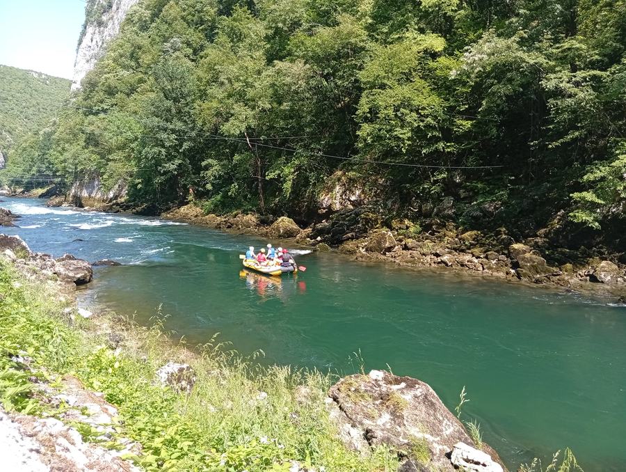 Rafting group waving from an inflatable raft on the green Vrbas river