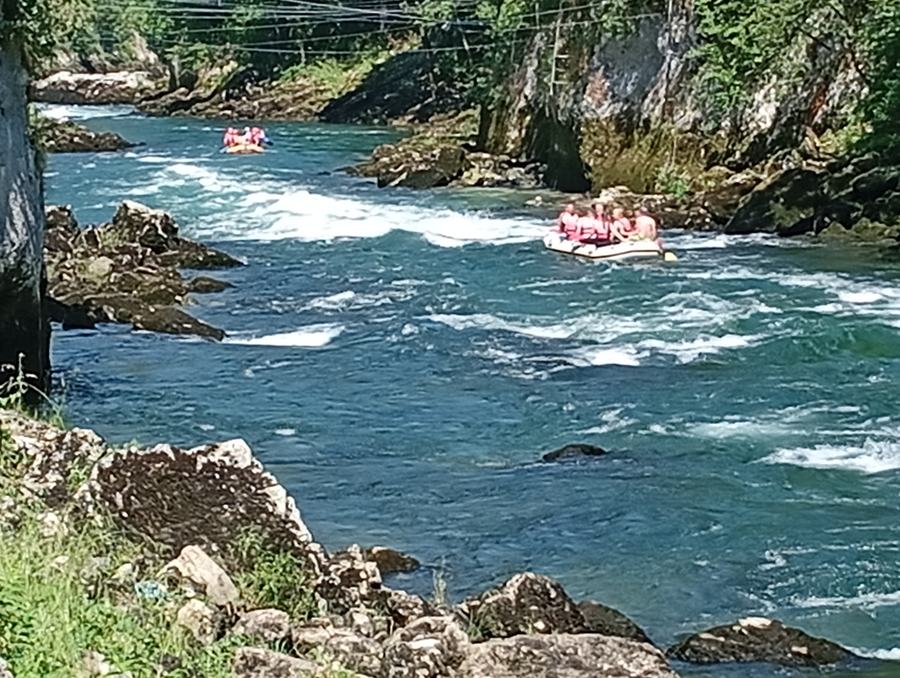 Yellow rafting boat with helmeted paddlers on the calm green Vrbas river